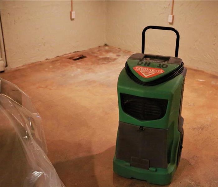 A SERVPRO machine in an empty basement