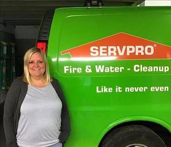 A woman standing next to a green SERVPRO van
