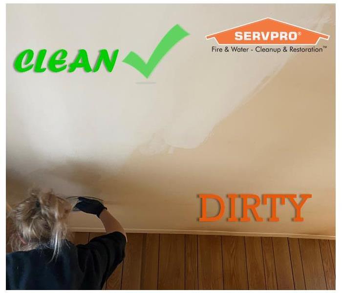 SERVPRO employee scrubbing a dirty ceiling with a cleaning rag showing drastic difference of cleaned and not cleaned areas.