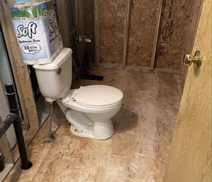 View inside a bathroom following removal of drywall, vinyl floor, and sink vanity.