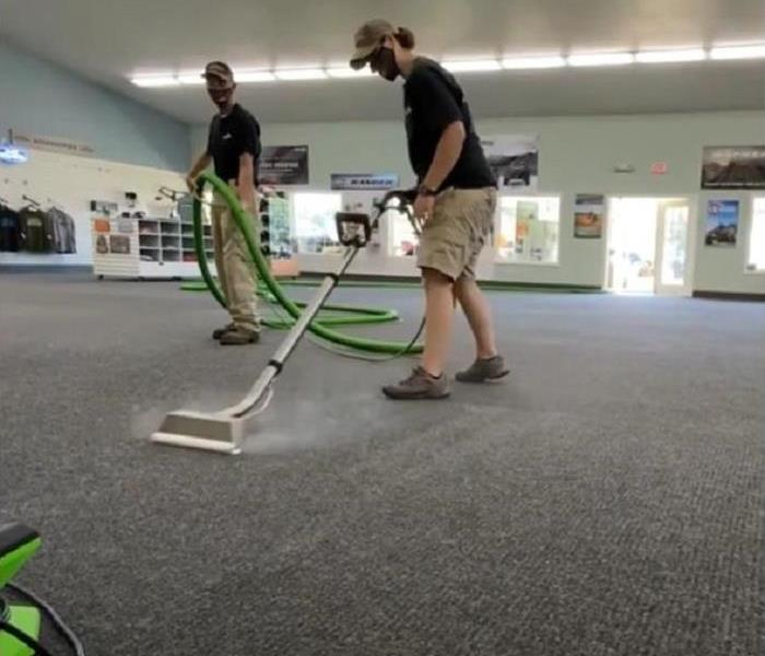 Technicians cleaning carpeting in a retail space.
