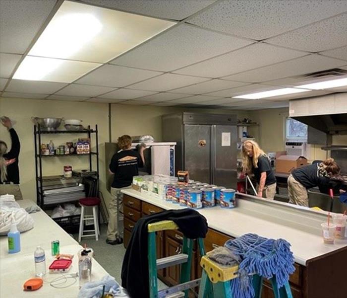 Team of workers cleaning in commercial kitchen.