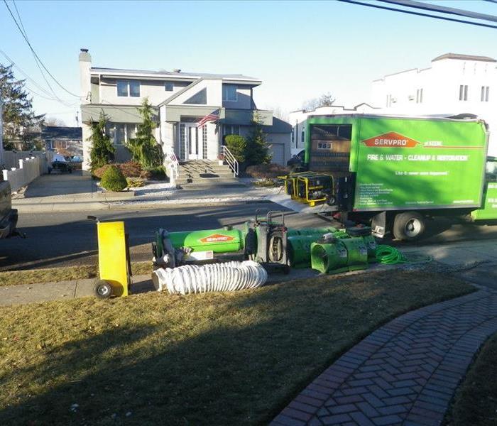 Green truck on side of street next to a temporary heating appliance.